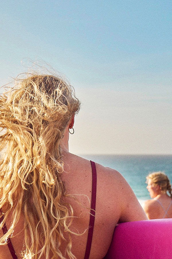 jente som sitter med ryggen til og ser utover havet