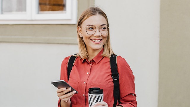 jente med mobil og kaffekopp